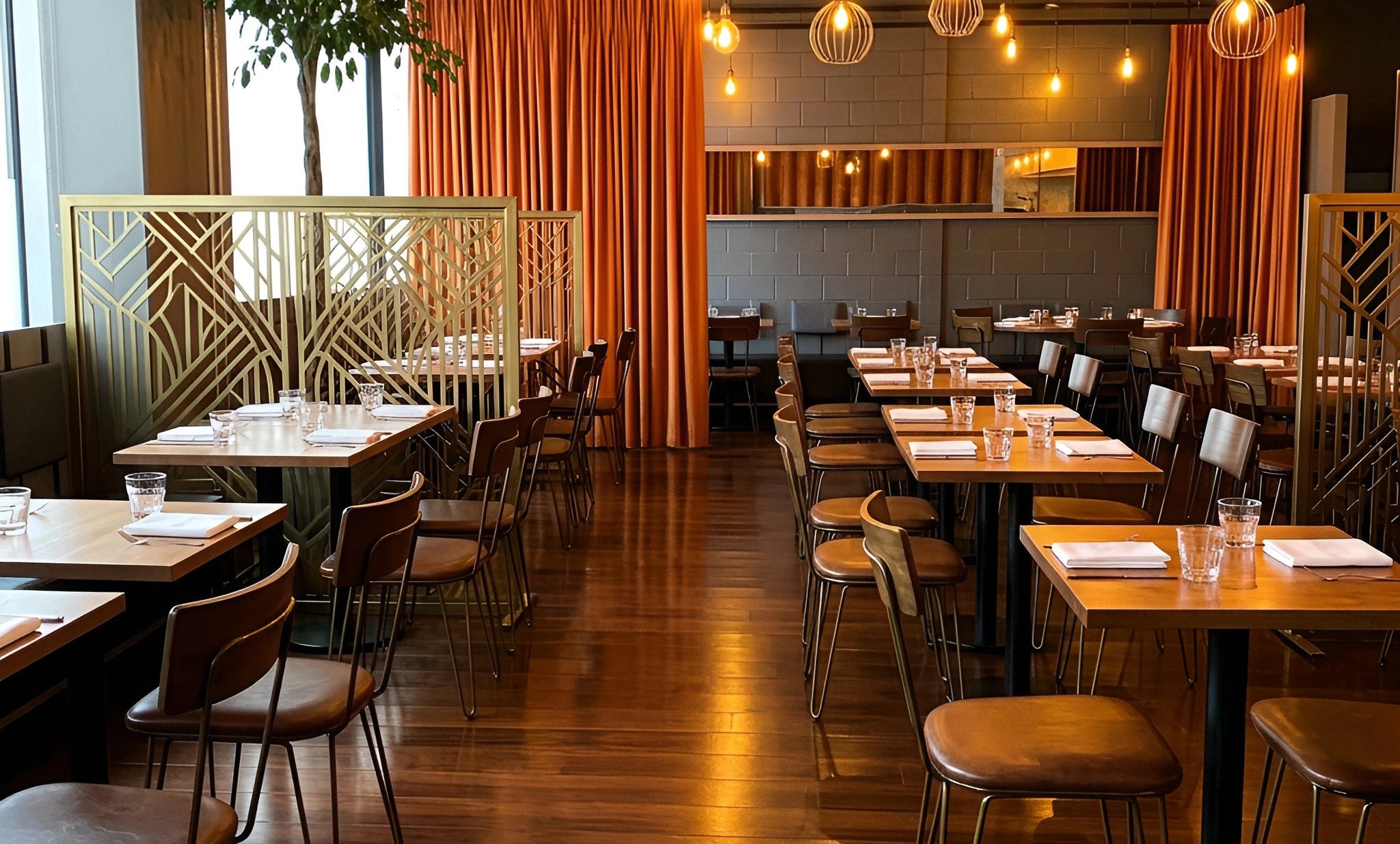 Laser-cut gold stainless screens dividing a restaurant