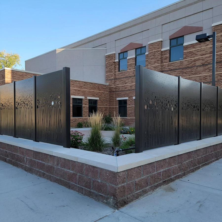 Matte black powder-coated laser-cut screens with a dandelion motif on a masonry plinth outside a civic building — visualization