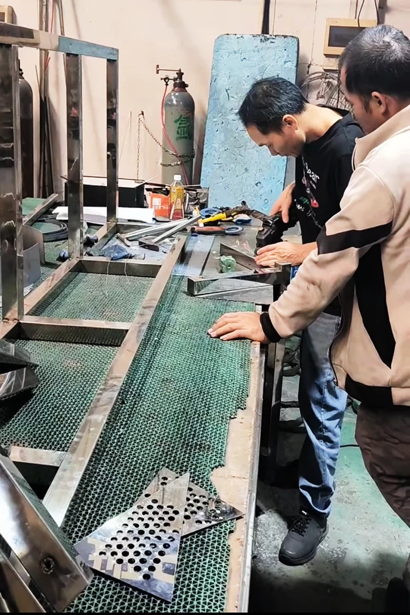 Technician hand-polishing TIG welded corner of a stainless steel frame for a seamless finish in the factory.